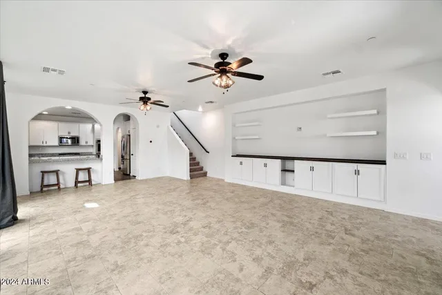 an empty room with chandelier fan and windows