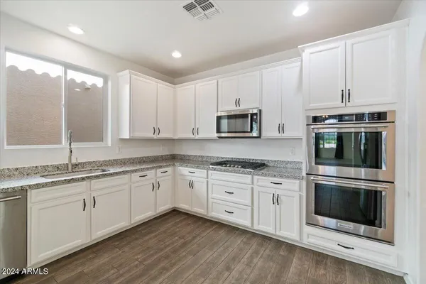 a kitchen with granite countertop white cabinets white stainless steel appliances and a sink