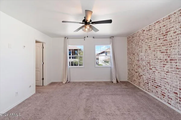 an empty room with windows and ceiling fan