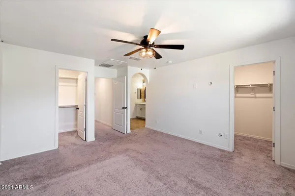 an empty room with closet and a ceiling fan