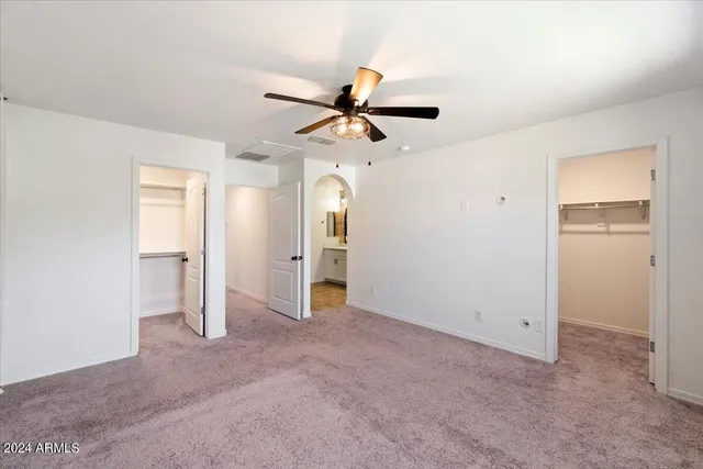 an empty room with closet and a ceiling fan