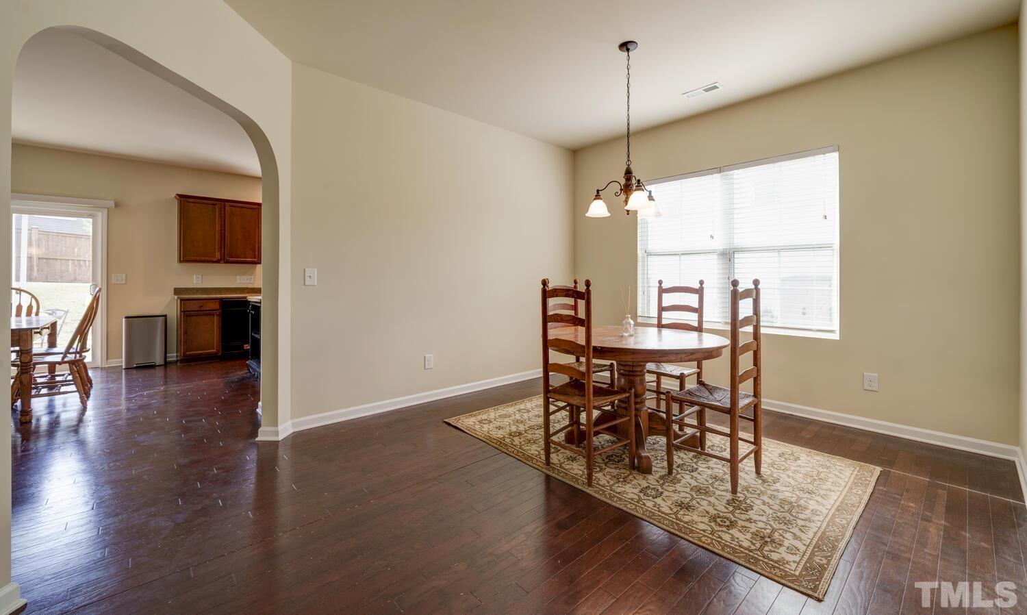 4104 Burnaby Street Raleigh, NC 27616 - Photo 19 of 59 a dining room with furniture wooden floor a rug and a chandelier