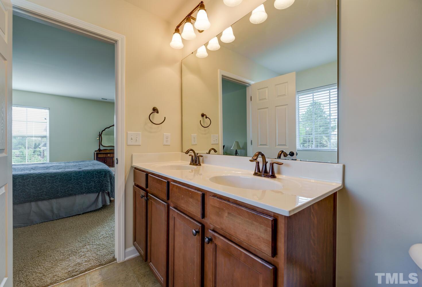 4104 Burnaby Street Raleigh, NC 27616 - Photo 24 of 59 a bathroom with a sink a vanity a mirror and a bathtub
