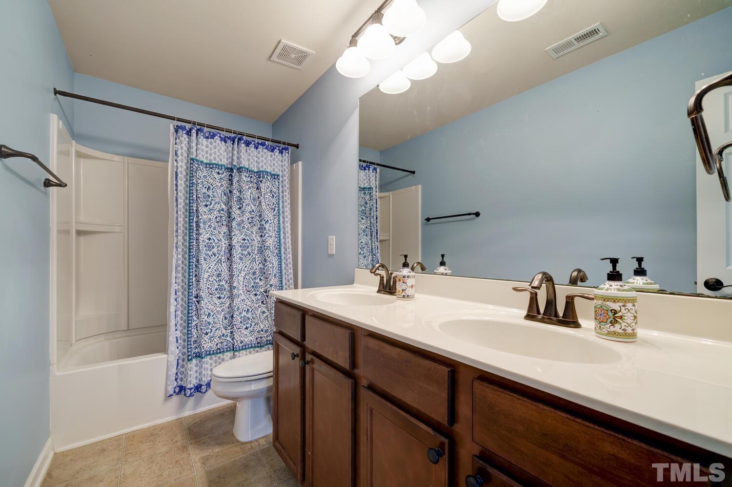 4104 Burnaby Street Raleigh, NC 27616 - Photo 37 of 59 a bathroom with a sink a toilet a mirror a bathtub and shower