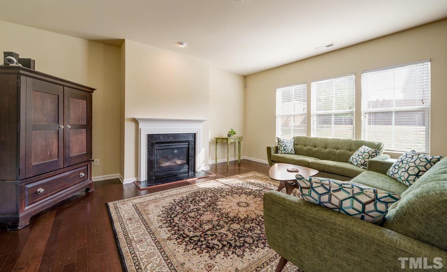 4104 Burnaby Street Raleigh, NC 27616 - Photo 5 of 59 a living room with furniture a fireplace and a flat screen tv