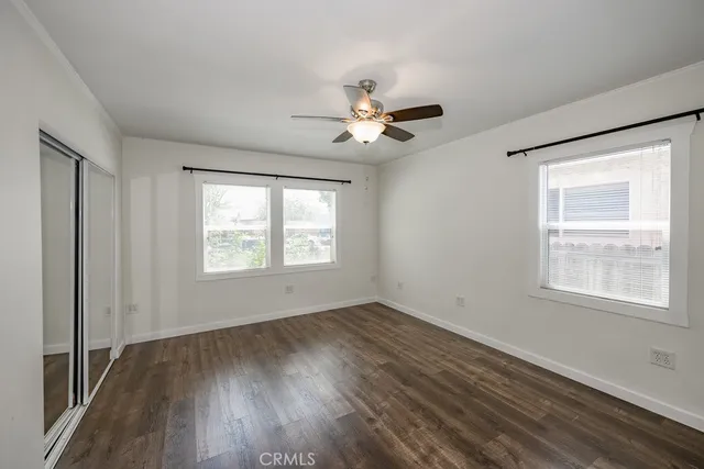 a view of an empty room with a window and wooden floor