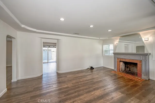 a view of an empty room with wooden floor fireplace and a window
