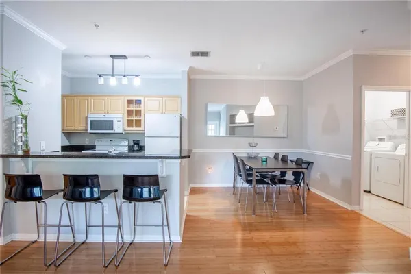 a kitchen with a dining table chairs and wooden floor