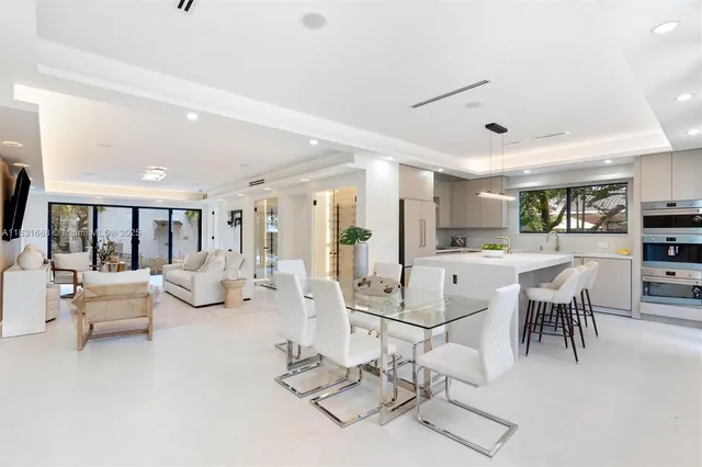 a living room with lots of white furniture and view of kitchen