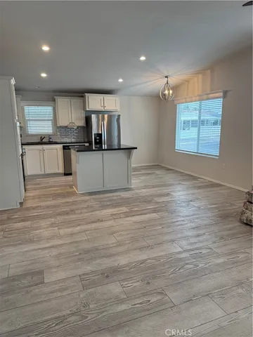 a view of kitchen with kitchen island stainless steel appliances wooden floor cabinets and a window