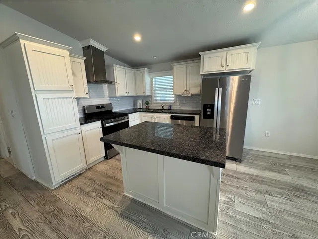 a kitchen with granite countertop a refrigerator a sink a stove a microwave and wooden floor