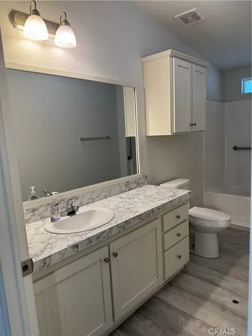 a bathroom with a granite countertop sink a toilet and mirror