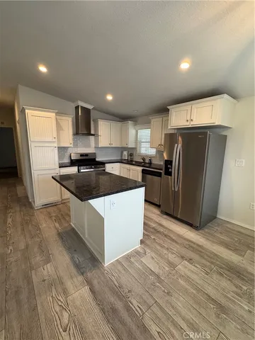 a kitchen with stainless steel appliances a refrigerator a sink a stove a microwave and wooden floor