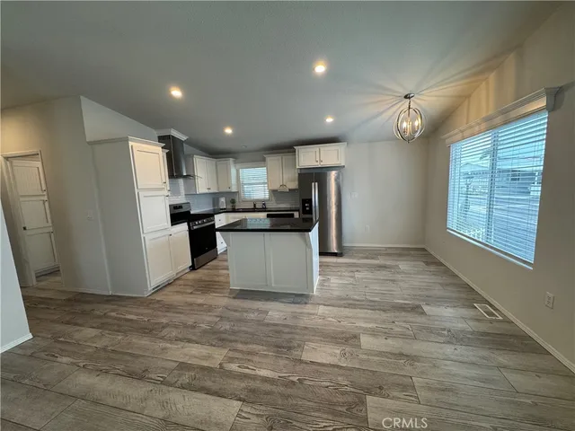a view of kitchen with kitchen island a sink wooden floor and refrigerator