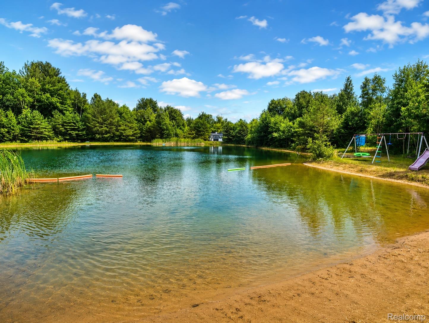 643 North Hockaday Road Gladwin, MI 48624 - Photo 10 of 24 Natural spring-fed pond featuring a sandy beach entry and a wooded perimeter