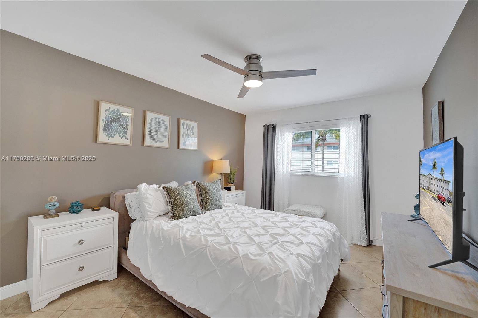 5300 Washington Street, Unit I203 Hollywood, FL 33021 - Photo 29 of 75 a bedroom with a bed and a flat tv screen on dresser