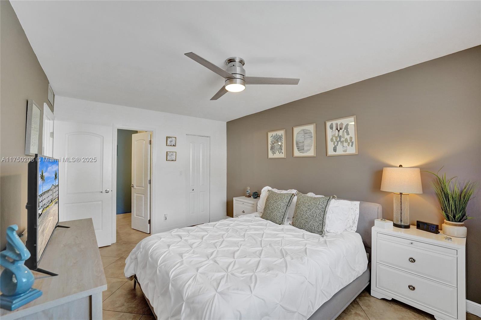 5300 Washington Street, Unit I203 Hollywood, FL 33021 - Photo 31 of 75 a bedroom with a large bed and a flat tv screen on dresser