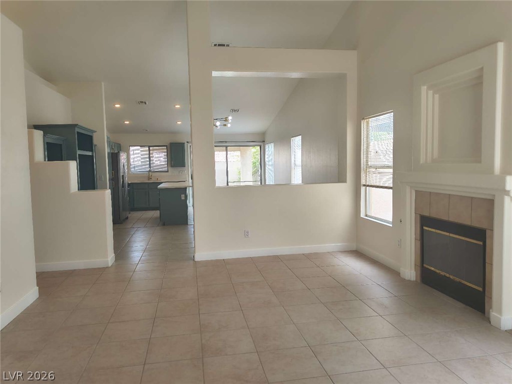 9725 Pima Point Avenue Las Vegas, NV 89147 - Photo 2 of 35 A well-lit interior space connects a spacious kitchen and living area, featuring a cozy fireplace.