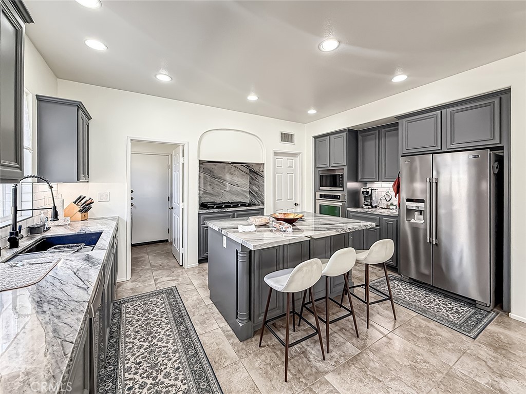 5244 Via Rincon Newbury Park, CA 91320 - Photo 10 of 19 a kitchen with refrigerator a stove a sink and a dining table with chairs