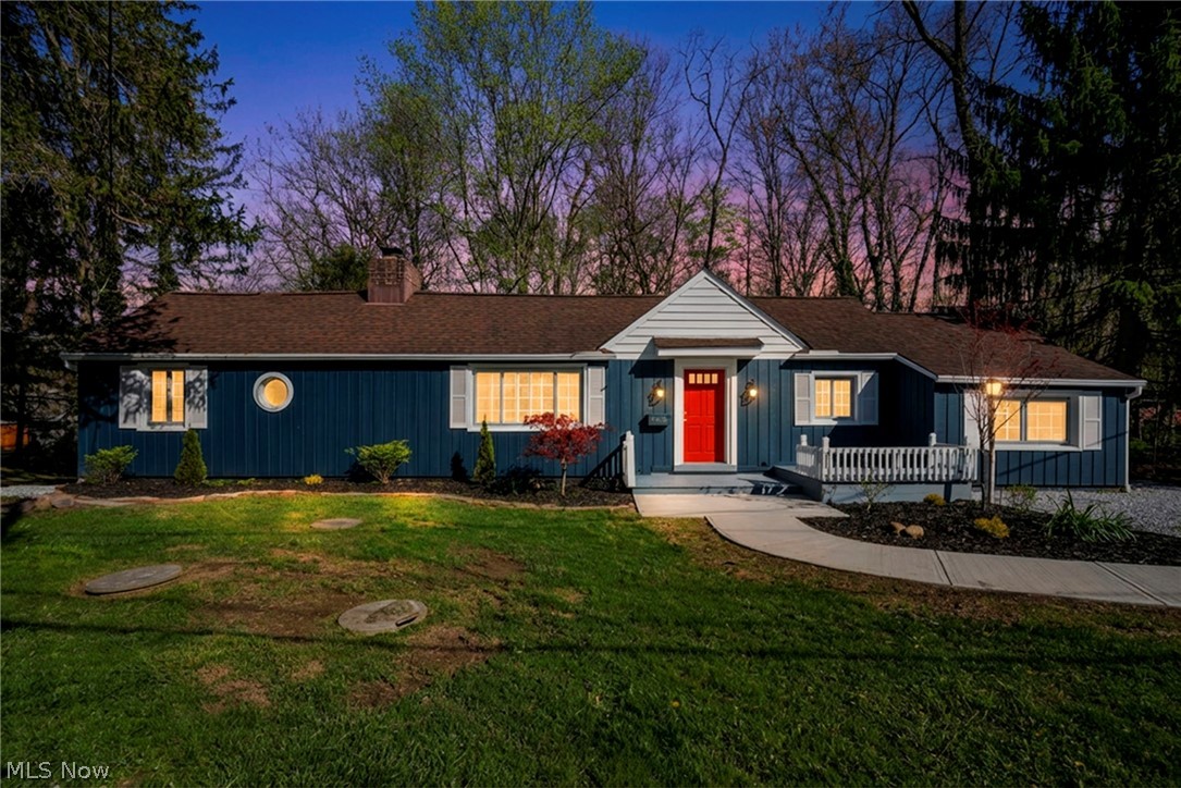 7339 River Road Olmsted Falls, OH 44138 - Photo 1 of 45 Ranch-style residence featuring deep blue siding, a vibrant red front door, white window shutters, a front porch with white railings, and a well-maintained lawn