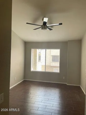 an empty room with wooden floor fan and windows