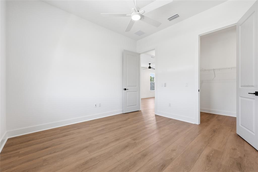1063 Southwest 135th Way Newberry, FL 32669 - Photo 31 of 42 an empty room with wooden floor and ceiling fan
