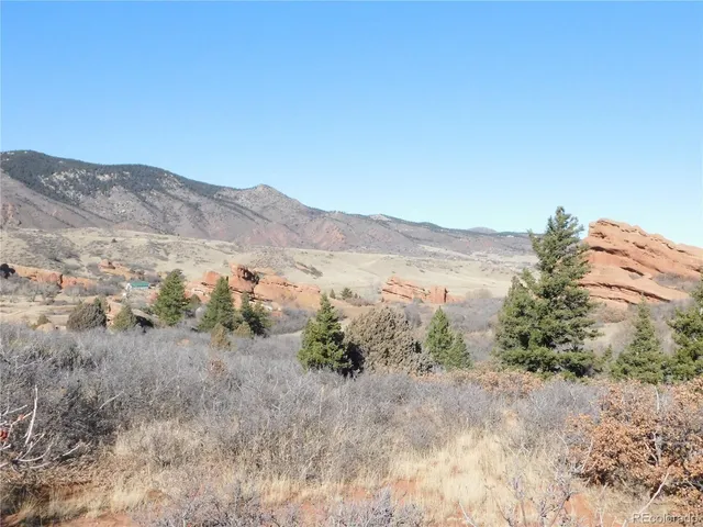 a view of a dry field with mountains in the background