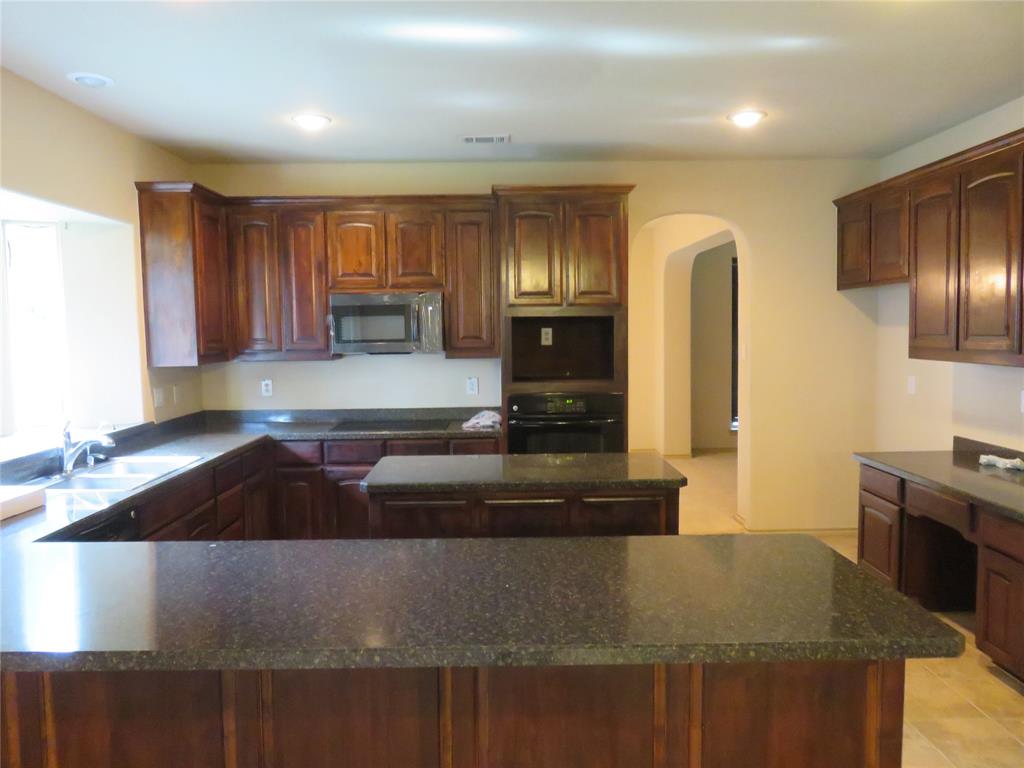1122 Walter Stephenson Road Midlothian, TX 76065 - Photo 7 of 26 Spacious kitchen featuring rich wood cabinetry, dark speckled countertops, a built-in microwave, and recessed ceiling lighting