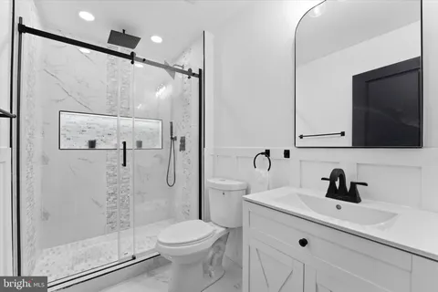 a bathroom with a toilet a sink a mirror and shower