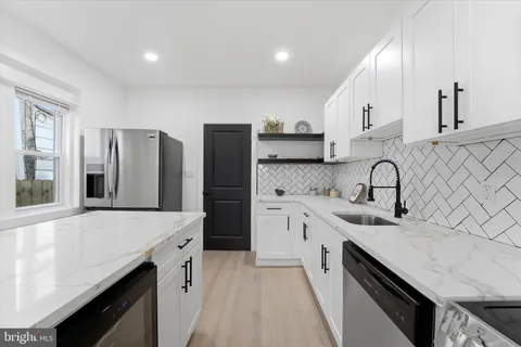 a kitchen with stainless steel appliances a sink dishwasher a refrigerator and a stove with wooden floor