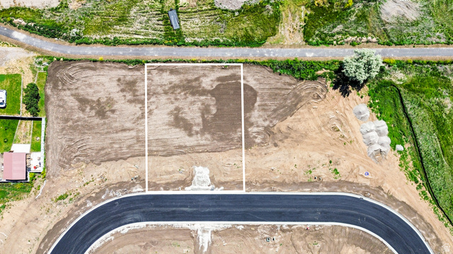 3230 South 1125th West, Unit 21 Logan, UT 84321 - Photo 3 of 20 Vacant land parcel with a clear boundary marking, featuring an established paved road frontage and surrounding natural green areas