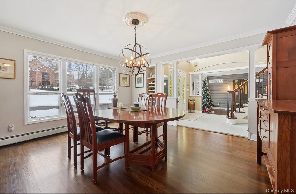 7 Gooler Court Stony Point, NY 10980 - Photo 9 of 35 Dining space featuring decorative columns, crown molding, stairs, dark wood-style floors, and a chandelier