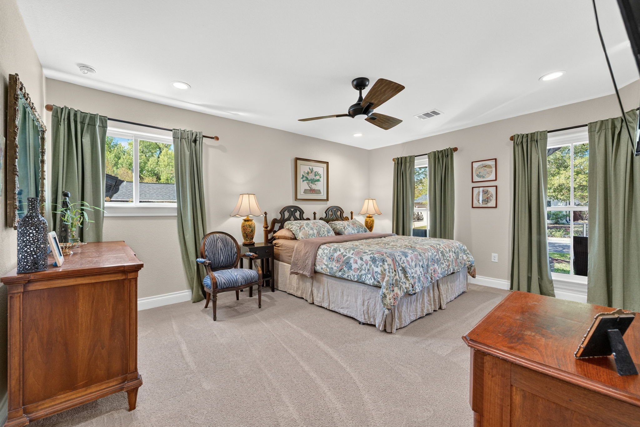 8611 Winding Walk Austin, TX 78757 - Photo 14 of 29 The spacious primary bedroom offers a peaceful retreat with plush carpeting, recessed lighting, and a modern ceiling fan. Large windows provide a view of the lush North Austin greenery.