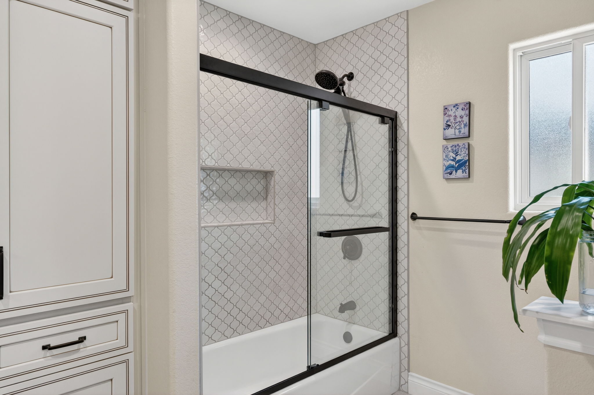 8611 Winding Walk Austin, TX 78757 - Photo 17 of 29 A closer look at the primary bath reveals a sophisticated tile shower surround framed by sleek hardware and a frosted window for privacy.