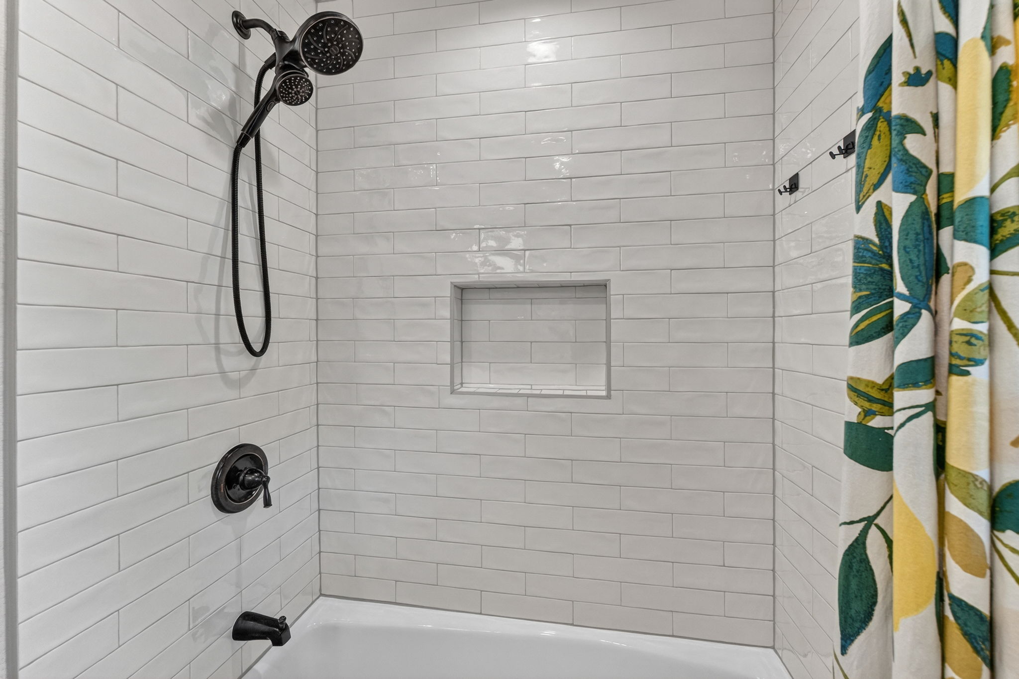 8611 Winding Walk Austin, TX 78757 - Photo 22 of 29 A clean, crisp retreat featuring floor-to-ceiling white subway tile with a built-in niche for essentials.