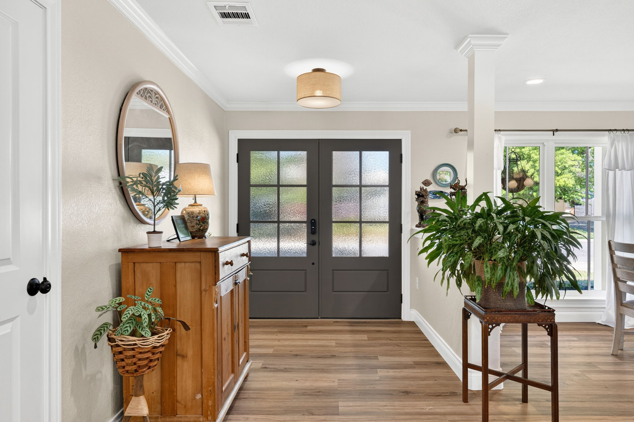 8611 Winding Walk Austin, TX 78757 - Photo 3 of 29 Step inside to a light-filled foyer where wide-plank flooring and soft, neutral tones immediately create a sense of calm. The handsome, dark-framed double doors with frosted glass offer privacy without sacrificing the natural light that defines this home.