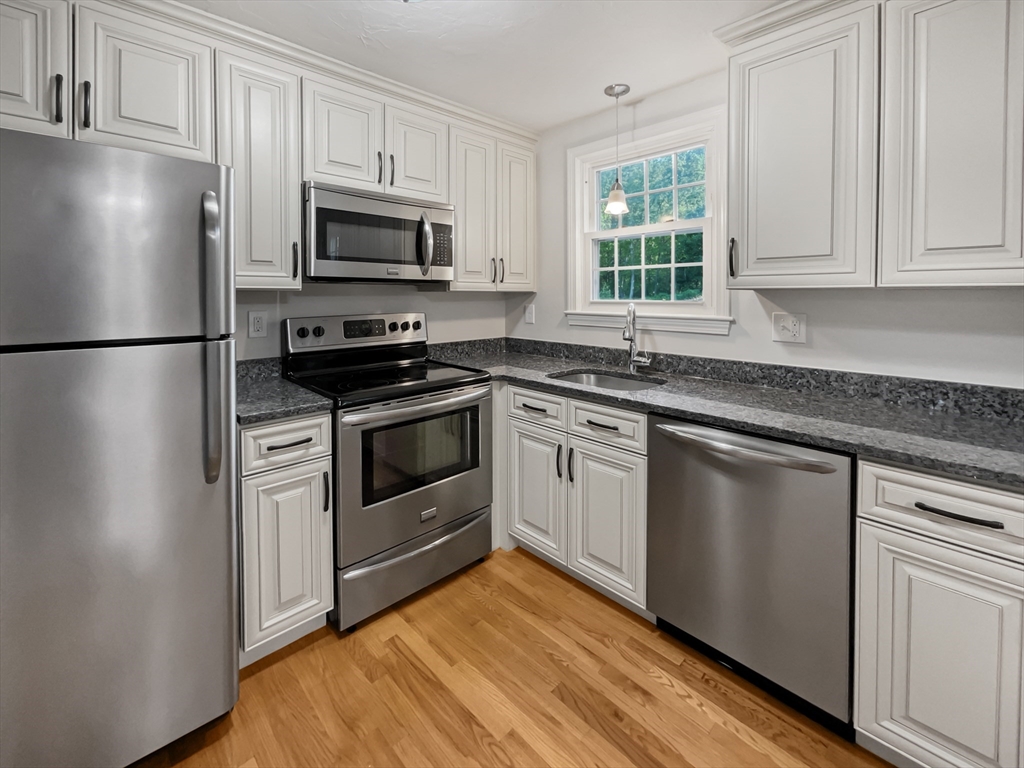 15 Cannongate Road, Unit 48 Tyngsborough, MA 01879 - Photo 6 of 25 a kitchen with white cabinets stainless steel appliances and window