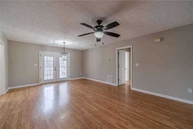 a view of an empty room with window and wooden floor