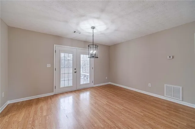a view of an empty room with wooden floor fridge and a window