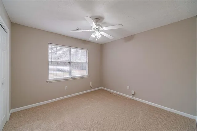 an empty room with a window and a fan