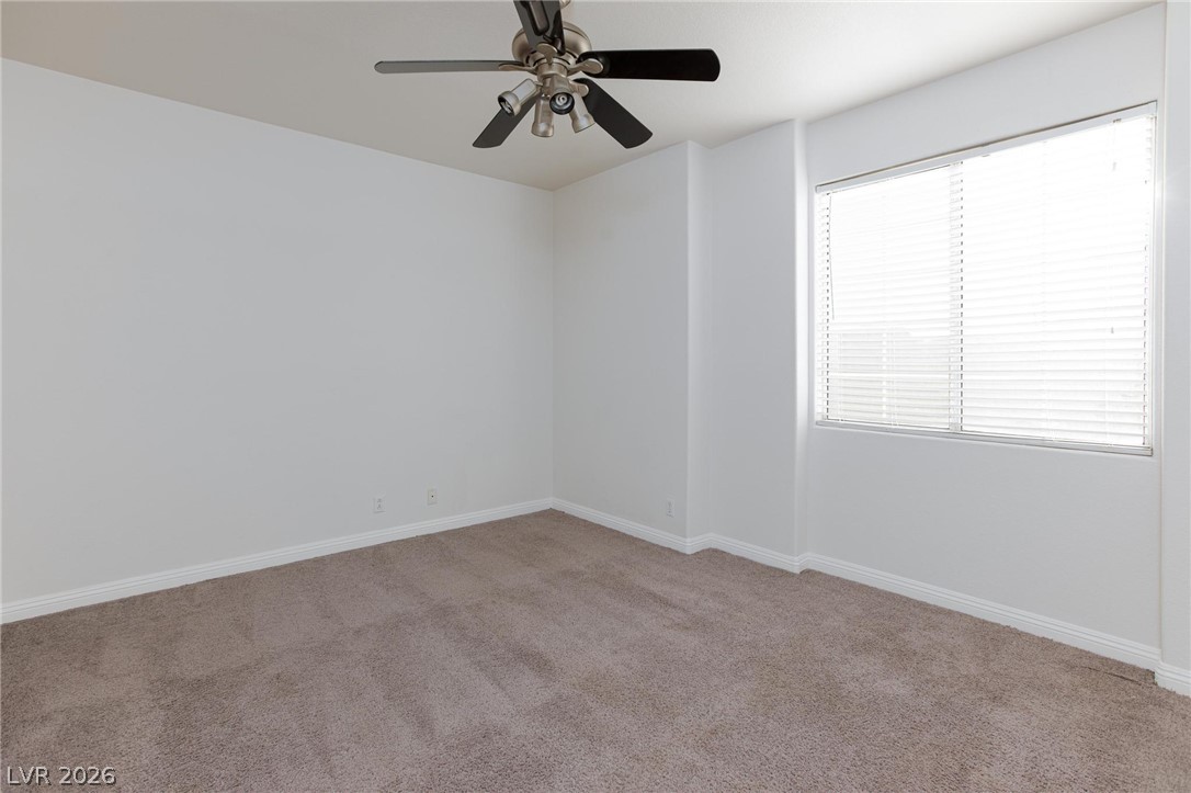 2246 Ramsgate Drive Henderson, NV 89074 - Photo 17 of 36 A well-lit bedroom features plush carpeting and a modern ceiling fan, ensuring comfort and style.