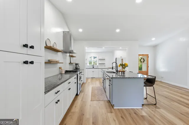 a kitchen with stainless steel appliances granite countertop a sink a stove and a wooden floors