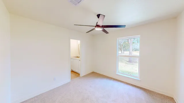 an empty room with windows and fan