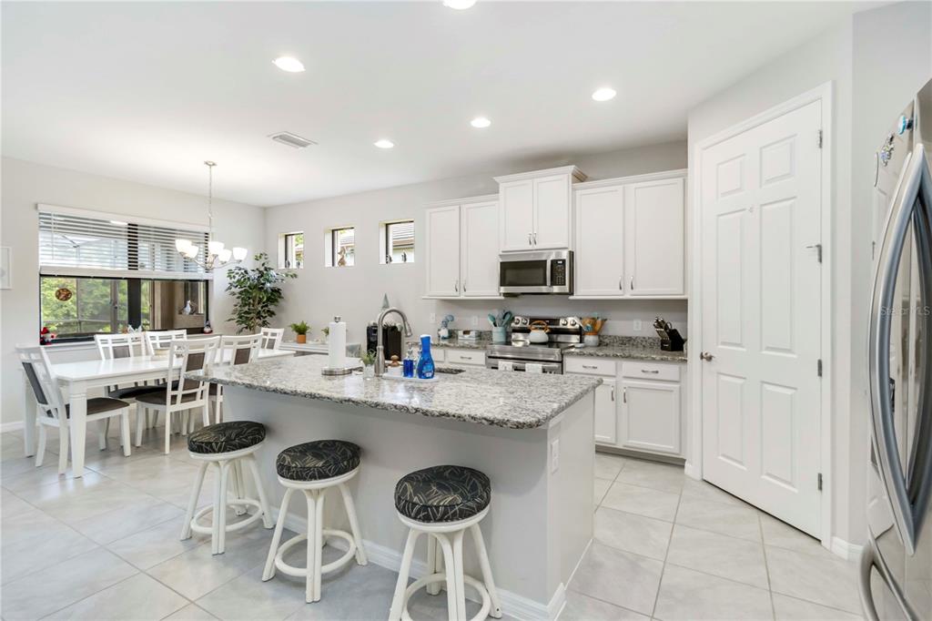 20765 Swallowtail Court Venice, FL 34293 - Photo 11 of 50 a kitchen with stainless steel appliances granite countertop a stove a sink a dining table and chairs