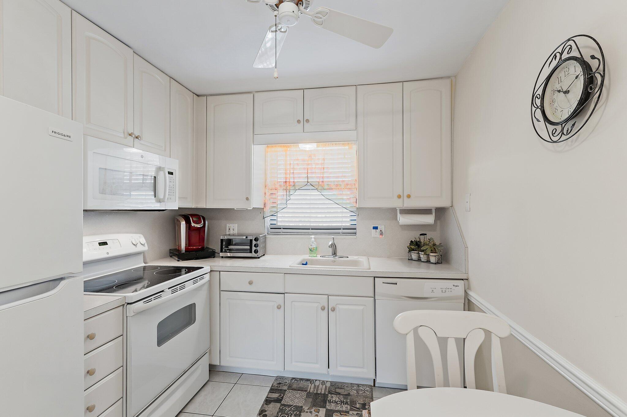 755 Saturn Street, Unit I 206 Jupiter, FL 33477 - Photo 5 of 26 a kitchen with white cabinets appliances and a sink