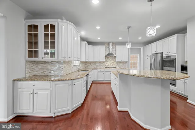 a kitchen with stainless steel appliances granite countertop a stove a sink dishwasher and a refrigerator with wooden floor