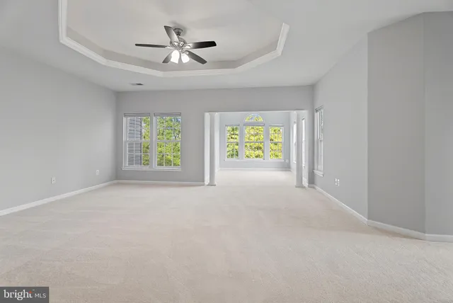 an empty room with windows and a ceiling fan
