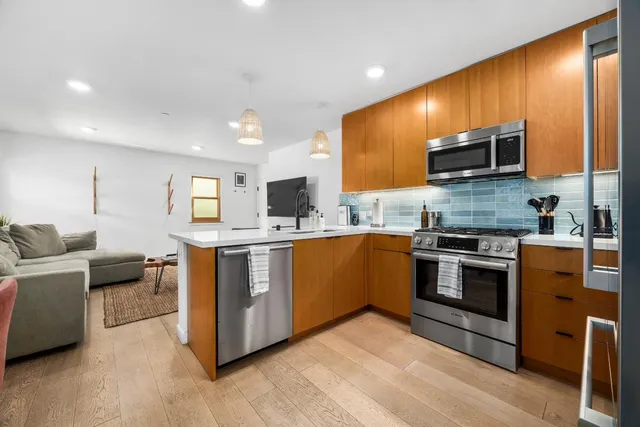 a kitchen with stainless steel appliances kitchen island granite countertop a stove top oven and sink