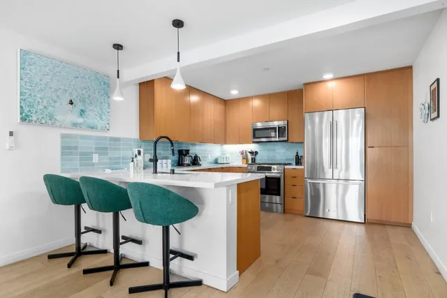 a kitchen with stainless steel appliances granite countertop a refrigerator a sink a stove a dining table and chairs