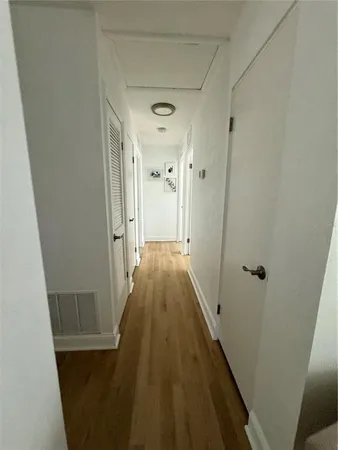 a view of a hallway with wooden floor and a bathroom